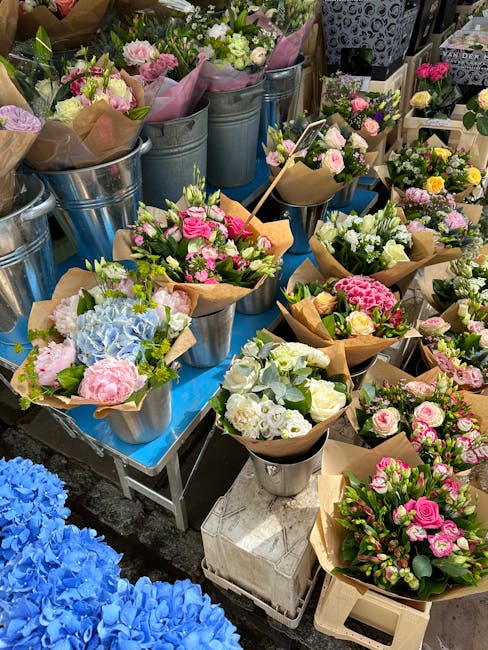 A display of freshly arranged flower bouquets at Hampstead Florist, featuring a variety of flowers in soft pastel pinks, whites, and vibrant greens. The bouquets are wrapped in brown kraft paper with 